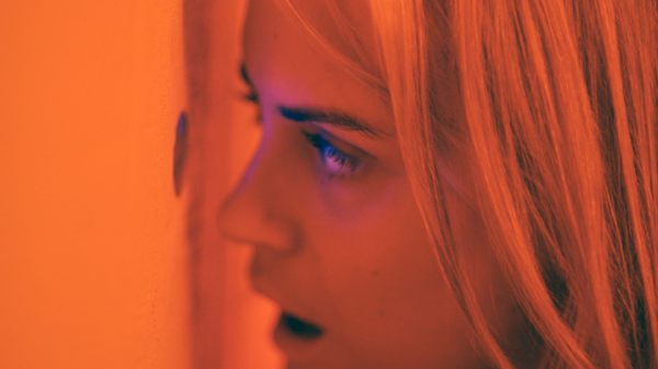 Emily (Taylor Schilling) looks through a peep hole at a massage parlor